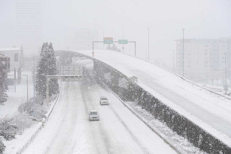 Cars drive along Interstate 705 as snow falls in Tacoma, Wash., on Saturday, Feb. 13, 2021. A winter storm blanketed the Pacific Northwest with ice and snow Saturday, leaving hundreds of thousands of people without power and disrupting travel across the region. (Joshua Bessex/The News Tribune via AP)
