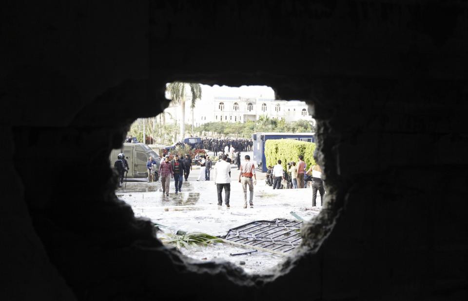 People and police are seen through a hole in the wall of the al-Azhar university administration building after students tried to break-in during student protests in Cairo October 30, 2013. Egyptian police fired teargas at protesting students at Cairo's al-Azhar university on Wednesday hours after authorities announced the detention of Muslim Brotherhood leader Essam El-Erian, part of a crackdown against the Islamist movement. (REUTERS/Mohamed Abd El Ghany)