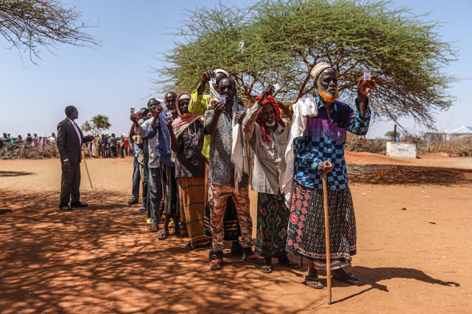 A group of displaced Somali men hold up their verification cards before receiving 