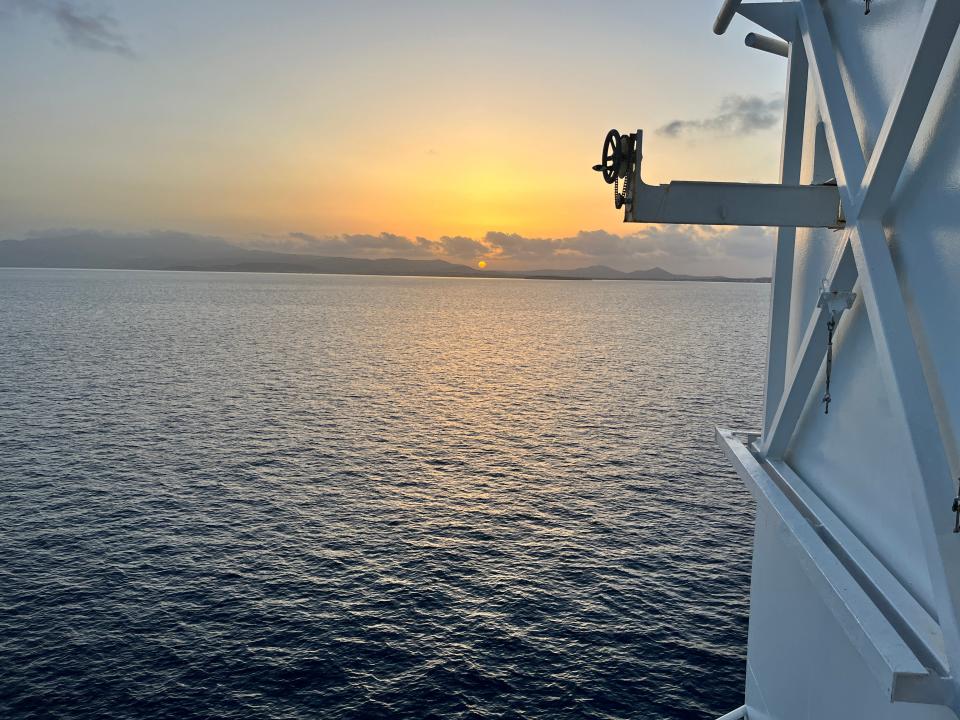 sunset off in the distance off the deck of a ferry ship