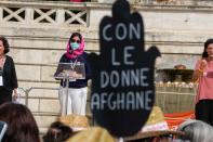 A banner reading "with Afghan women" is seen as an Afghan refugee, who denied to give her name for safety reasons, delivers her speech during a demonstration in favor of Afghan women's rights, staged by women rights activists, in Rome, Saturday, Sept. 25, 2021. (AP Photo/Andrew Medichini)