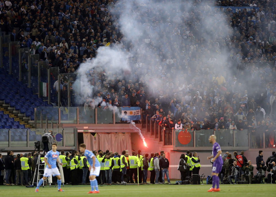 Napoli fans throw flares prior to the start of Italian Cup final match between Fiorentina and Napoli in Rome's Olympic stadium Saturday, May 3, 2014. At least one fan and one police officer were reportedly shot before the Italian Cup final between Napoli and Fiorentina, and the fan was in serious condition. As a result, the start of the final was delayed, and there were scenes of violence inside the stadium with a firefighter injured by fireworks thrown from the stands. The shootings occurred in an area where Napoli fans were gathering for the match, the ANSA news agency reported. (AP Photo/Gregorio Borgia)