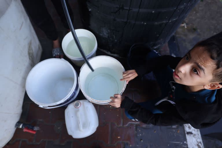 Un joven palestino llena un cubo de agua en el campamento de refugiados de Rafah, en el sur de la Franja de Gaza, el 17 de octubre de 2023.