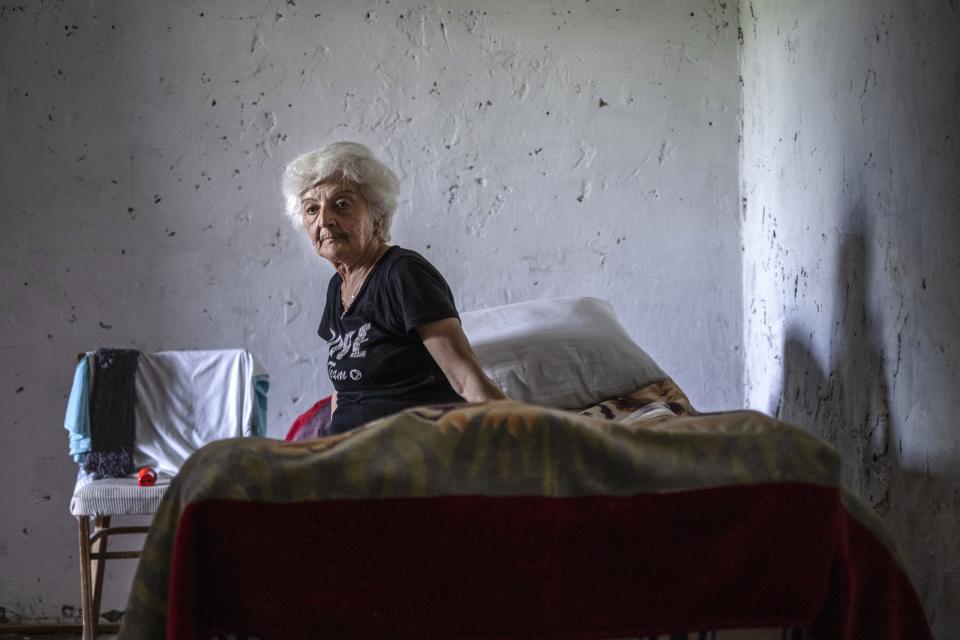 Anahit Aleqyan sits on a bed in the empty room of her new house in Shurnukh village, about 200 km. (125 miles) south east of Yerevan, Armenia, Tuesday, June 15, 2021. Anahit Aleqyan, a 65-year-old from the village of Shurnkh in southern Armenia, says that her village was cut in two by a newly defined border with Azerbaijan, and she lost her house in the peace deal. "Every day I come here to gather thyme, look at (my house) and cry," she lamented. (AP Photo/Areg Balayan)