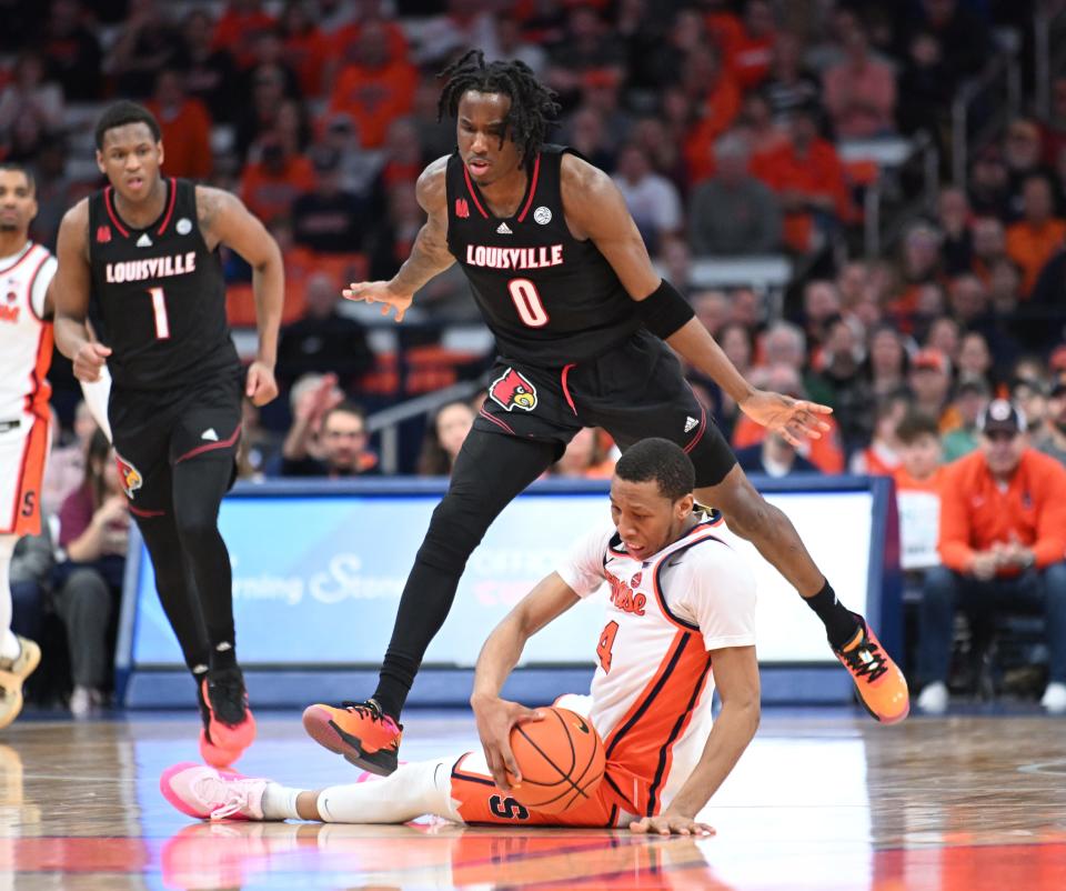 Syracuse Orange forward Chris Bell is tripped by Louisville Cardinals guard Mike James.