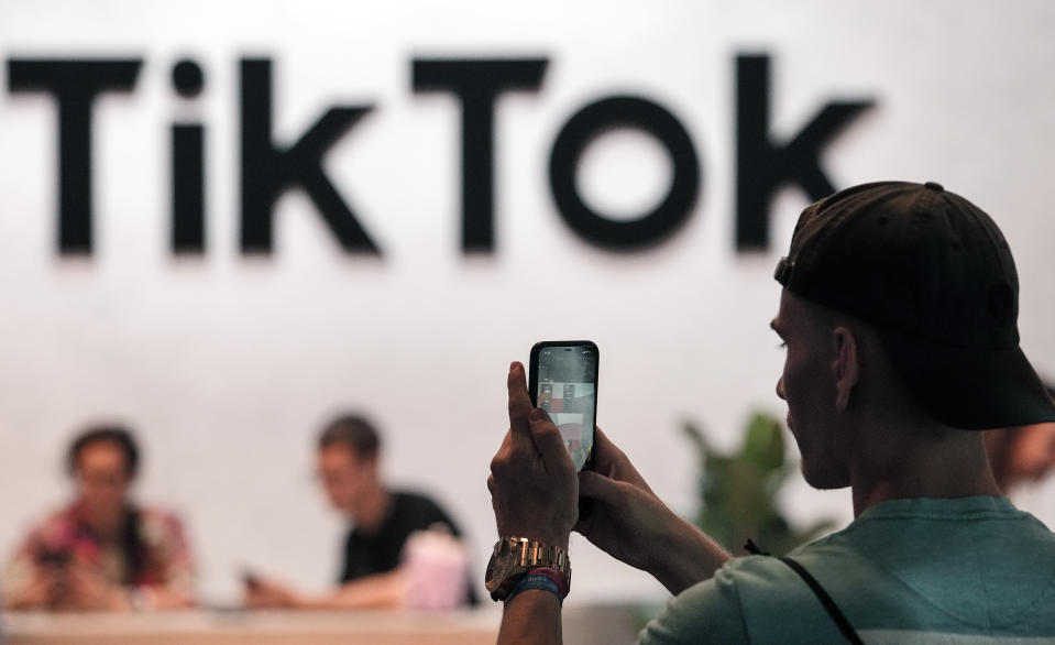 A visitor takes a photo at the TikTok exhibition stands at the Gamescom computer games fair in Cologne, Germany, Thursday, August 25, 2022. Around 1,100 exhibitors from 53 countries await tens of thousands of gaming enthusiasts daily for the first time since COVID-19 at the biggest gaming event in the world.  (AP Photo/Martin Meissner)