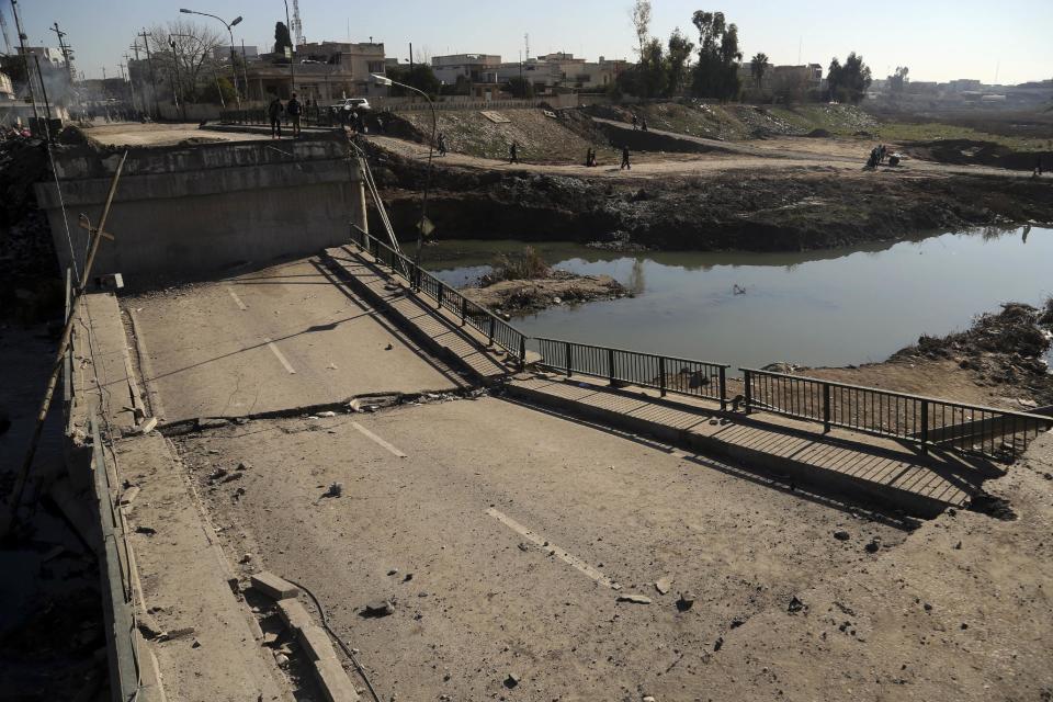 People inspect a bridge destroyed by Islamic State militants in a neighborhood recently liberated from Islamic State on the eastern side of Mosul, Iraq, Thursday, Jan. 12, 2017. Small stalls and carts have sprung up outside the bombed-out restaurants and cafes in eastern Mosul, selling fresh vegetables, cigarettes and cellphones to the thousands of civilians still living in neighborhoods where the Iraqi military has driven out the extremists of the Islamic State group.(AP Photo/ Khalid Mohammed)