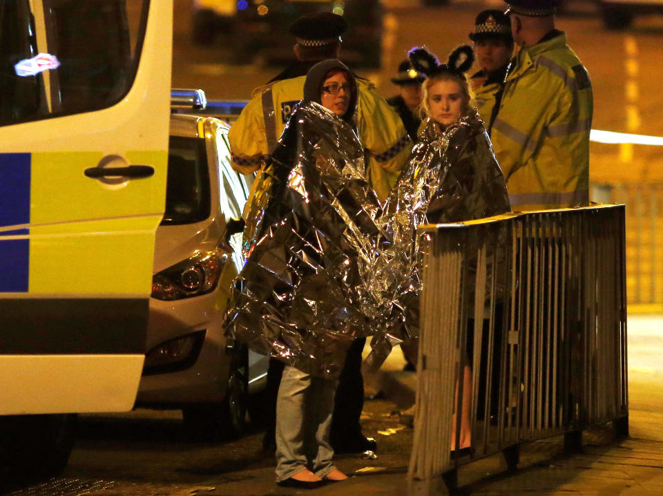 Two women wrapped in thermal blankets stand near the Manchester Arena.&nbsp;