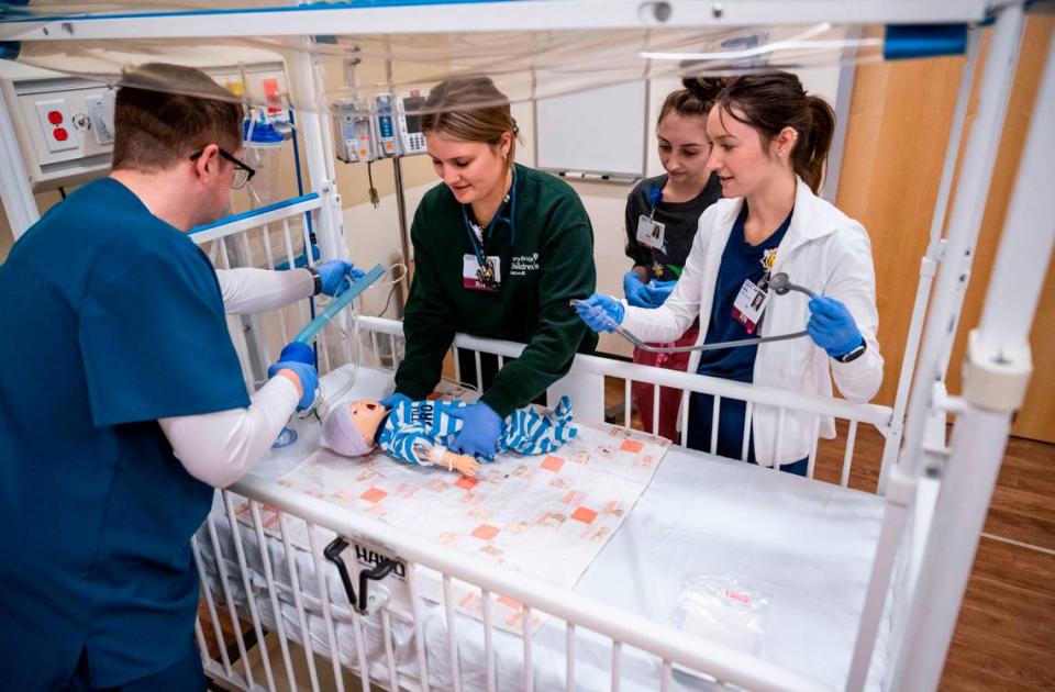 Mary Bridge Children’s hospital RN residents Matthew Wald, left, Grace Portch, center, Karli Priebe, second from right, and Haley Jones, right, participate in a simulation where they treat a “pediatric patient” with seizures and symptoms of abuse as part of MultiCare University’s pediatric nurse residency program at MultiCare University in Puyallup on March 31, 2023.