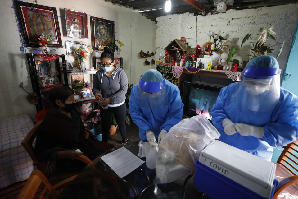 Doctors Delia Caudillo, center, and Monserrat Castaneda, prepare to conduct a COVID-19 test on 82-year-old Modesta Caballero Serrano, as her granddaughter gives her antibacterial gel, at her home in the Venustiano Carranza borough of Mexico City, Thursday, Nov. 19, 2020. (AP Photo/Rebecca Blackwell)