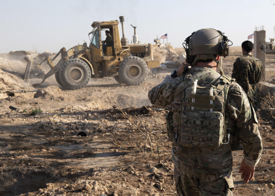 In this Aug. 22, 2019 photo, provided by the U.S. Army, shows A U.S. service member watches as Syrian Democratic Forces remove military fortifications during the implementation of the security mechanism along the Turkey-Syria border in northeast Syria. Ilham Ahmed, co-chair of the executive committee of the U.S-backed Syrian Democratic Council said Tuesday, Sept. 3, 2019, that the creation of a so-called “safe zone” in northeastern Syria is off to good start, with U.S.-backed Kurdish-led forces pulling back from an initial part of the border with Turkey, but calm can only prevail if Turkey also removes its troops. (Spc. Alec Dionne/U.S. Army via AP )