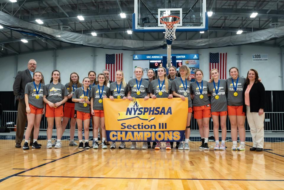 The Cooperstown Hawkeyes pose with their banner after beating Weedsport Saturday in Section III's Class C final at SRC Arena.