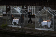 FILE - In this May 5, 2020 file photo, staff at the Mediamatic restaurant serve food to volunteers seated in small glasshouses during a try-out of a setup which respects social distancing abiding by government directives to combat the spread of the COVID-19 coronavirus in Amsterdam, Netherlands. Restaurants around the world try to lure back clientele while keeping them virus-free. (AP Photo/Peter Dejong, File)