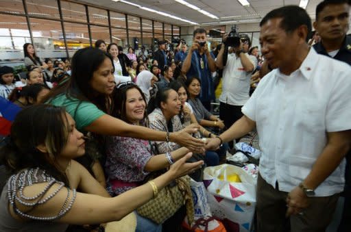 Philippine Vice-President Jejomar Binay (R) welcomes women workers, who had been working in Syria, after they disembarked from a plane chartered by the International Organization for Migration at the international airport in Manila