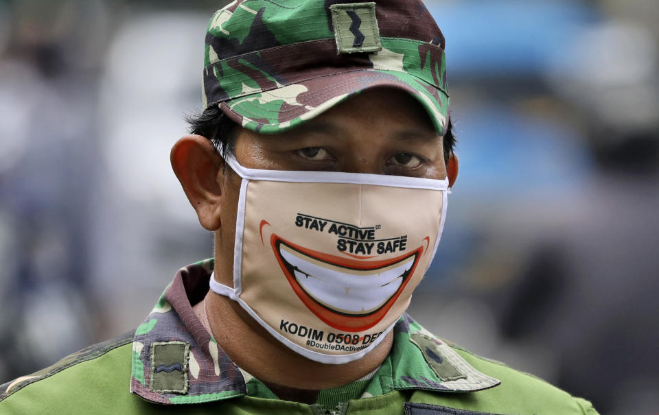 An Indonesian soldier wears face mask as he and his team man a checkpoint during the large-scale restriction imposed by the local government to curb the spread of the coronavirus outbreak in Jakarta, Indonesia, Wednesday, April 15, 2020. Indonesia's capital kicked off the stricter restriction last week as the metropolitan area has become Indonesia's coronavirus epicenter. (AP Photo/Dita Alangkara)