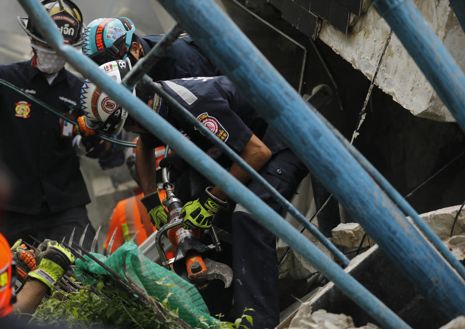 Rescue teams use rescue cutters as they search for possible victims trapped in a house that collapsed in Bangkok, Thailand, Saturday, April 3, 2021. A number of people were killed after a three-story house in Bangkok collapsed on Saturday due to fire, the city government said. (AP Photo/Str)