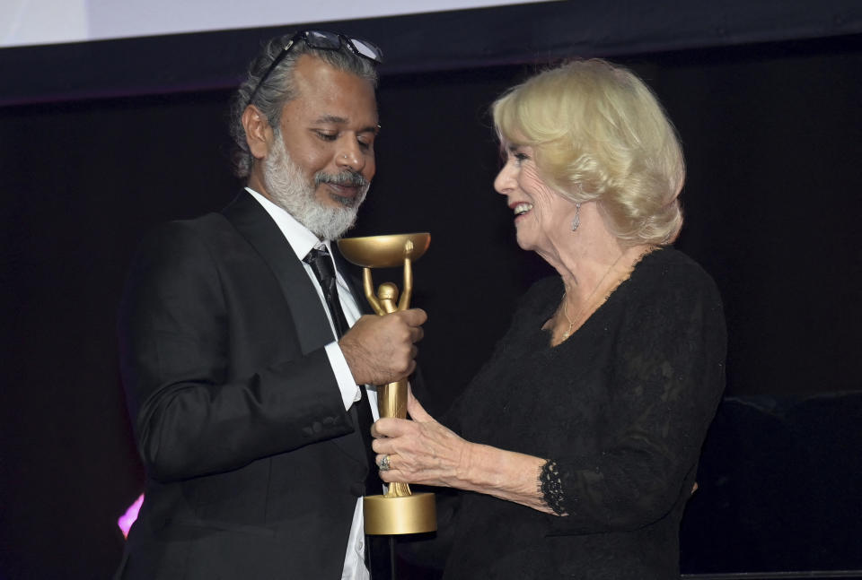 Britain's Camilla, Queen Consort, presents winner Shehan Karunatilaka with the trophee for "The Seven Moons of Maali Almeida" during the Booker Prize at the Roundhouse in London, Monday Oct. 17, 2022. (Toby Melville/Pool via AP)