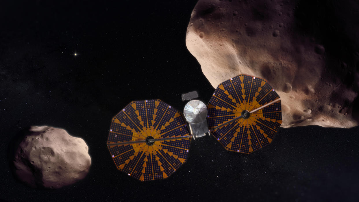  An artist's depiction of the Lucy spacecraft flying past a pair of Trojan asteroids. 