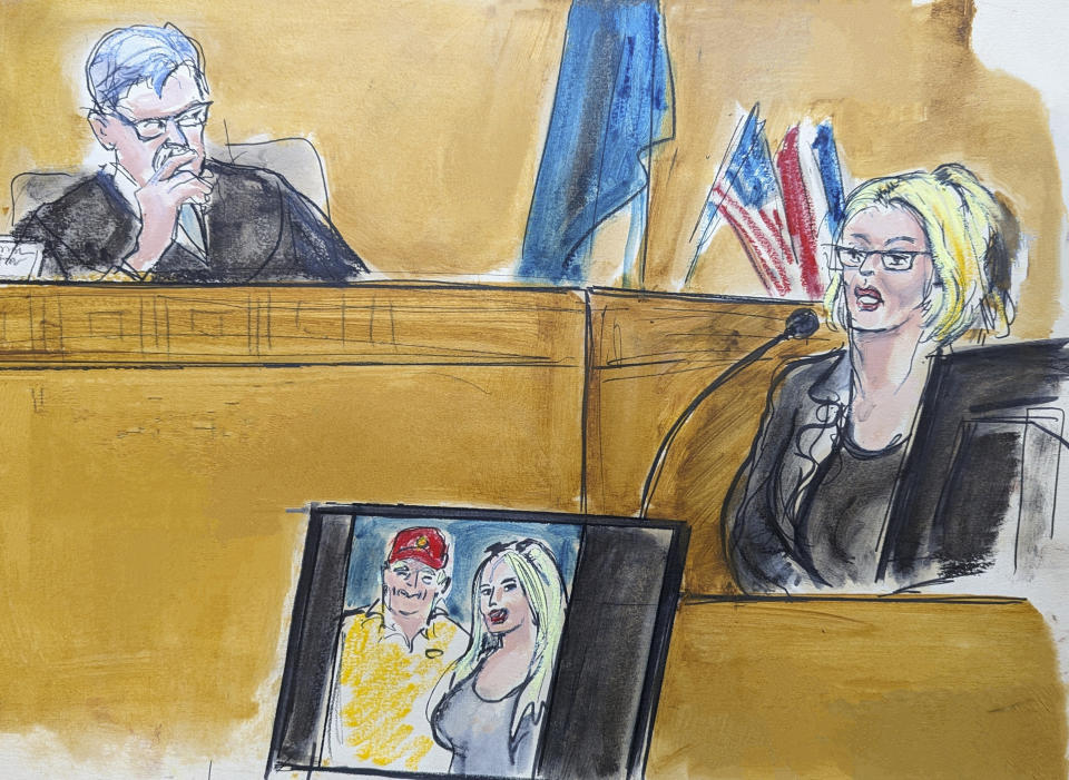 In this courtroom sketch, Stormy Daniels testifies on the witness stand as Judge Juan Merchan looks on in Manhattan criminal court, Tuesday, May 7, 2024, in New York.. A photo of Donald Trump and Daniels from their first meeting is displayed on a monitor. (Elizabeth Williams via AP)