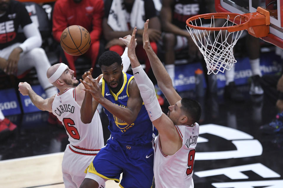 Golden State Warriors' Andrew Wiggins (22) vies against Chicago Bulls' Alex Caruso (6) and Nikola Vucevic (9) for a rebound during the first half of an NBA basketball game Friday, Jan 12, 2024, in Chicago. (AP Photo/Paul Beaty)