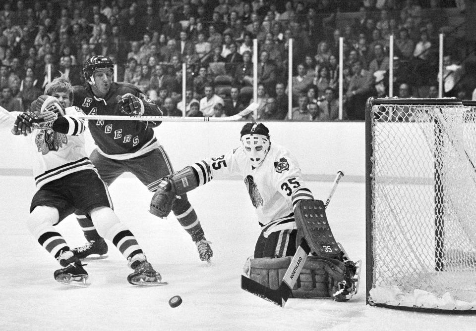 FILE - In this April 15, 1972, file photo, New York Rangers left winger Pete Stemkowski (21) puts his arm around the neck of Chicago Blackhawks defenseman Keith Magnuson (3) after firing a shot on Blackhawks goalie Tony Esposito (35) during the opening game of an NHL hockey Stanley Cup second-round playoff series in Chicago. Esposito, a Hall of Fame goaltender who played almost his entire 16-year career with the Blackhawks, has died following a brief battle with pancreatic cancer, the team announced Tuesday, Aug. 10, 2021. He was 78. (AP Photo/Fred Jewell, File)