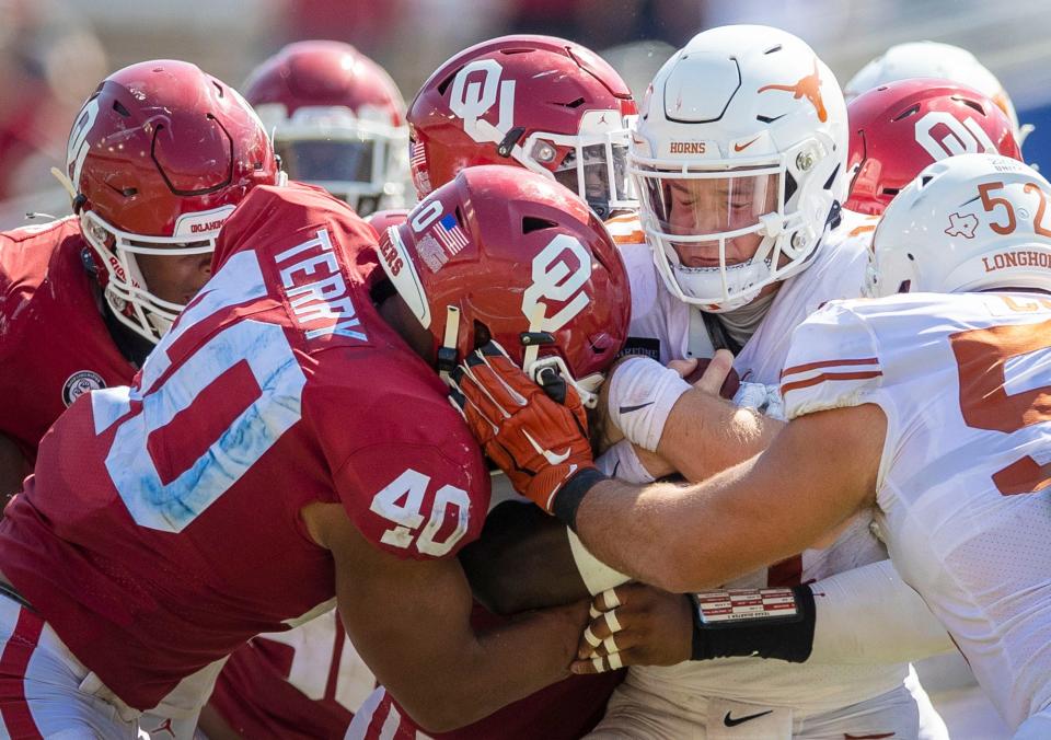 Texas Longhorns quarterback Sam Ehlinger (11) fights for yardage against Oklahoma Sooners defense in an NCAA college football game at the Cotton Bowl in Dallas.