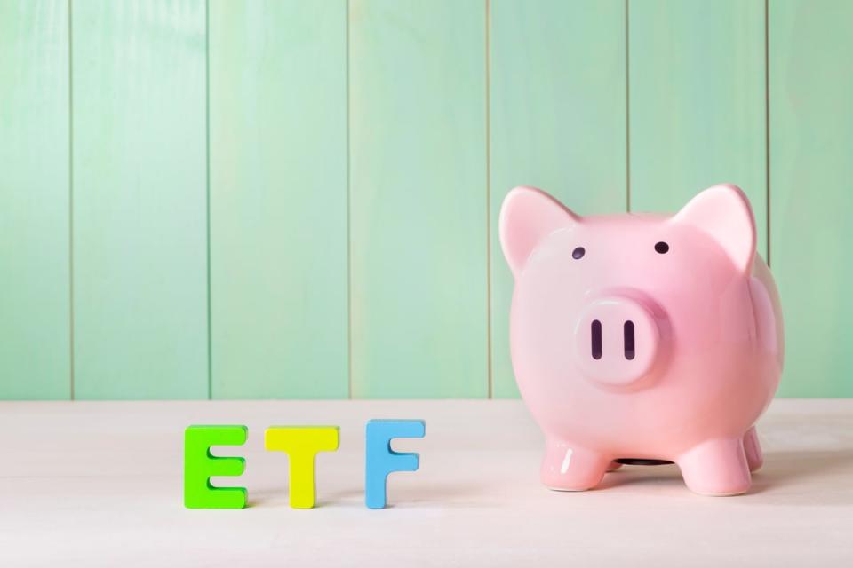 Blocks spelling ETF standing next to a piggy bank.