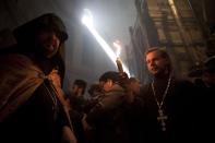 A Christian priest holds a candle at the church of the Holy Sepulcher, traditionally believed to be the burial site of Jesus Christ, during the ceremony of the Holy Fire in Jerusalem's Old City, Saturday, April 19, 2014. The "holy fire" was passed among worshippers outside the Church and then taken to the Church of the Nativity in the West Bank town of Bethlehem, where tradition holds Jesus was born, and from there to other Christian communities in Israel and the West Bank. (AP Photo/Dan Balilty)