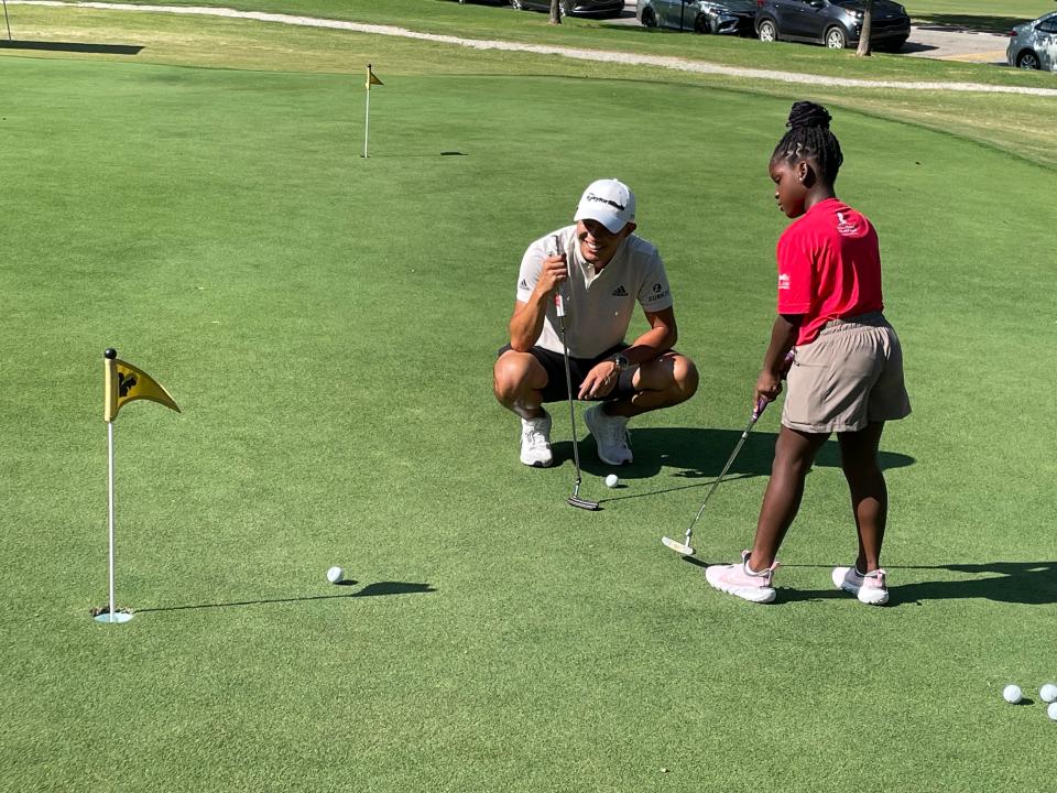 Collin Morikawa gives putting pointers to St. Jude patient Azalea as she practices during a golf clinic at the Overton Park 9 ahead of the 2022 FedEx St. Jude Championship.