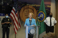 Seattle Mayor Jenny Durkan, center, speaks Monday, July 13, 2020, during a news conference at City Hall in Seattle as Police Chief Carmen Best, left, and Fire Chief Harold Scoggins , right, look on. Durkan and Best were critical of a plan backed by several city council members that seeks to cut the police department's budget by 50 percent. (AP Photo/Ted S. Warren)