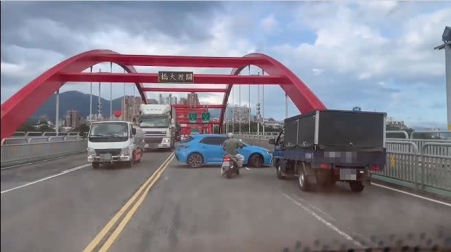 一輛藍色自小客車在關渡橋「壓雙黃線無敵大迴轉」。（圖／翻攝自臉書社團「細說淡水」）