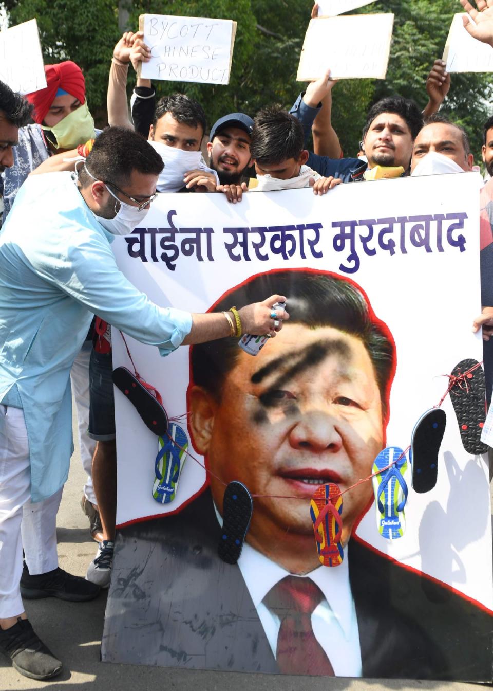 Activists of the ruling Bharatiya Janata Party spray black paint on a poster depicting Chinese President Xi Jinping during a protest against China (AFP via Getty)