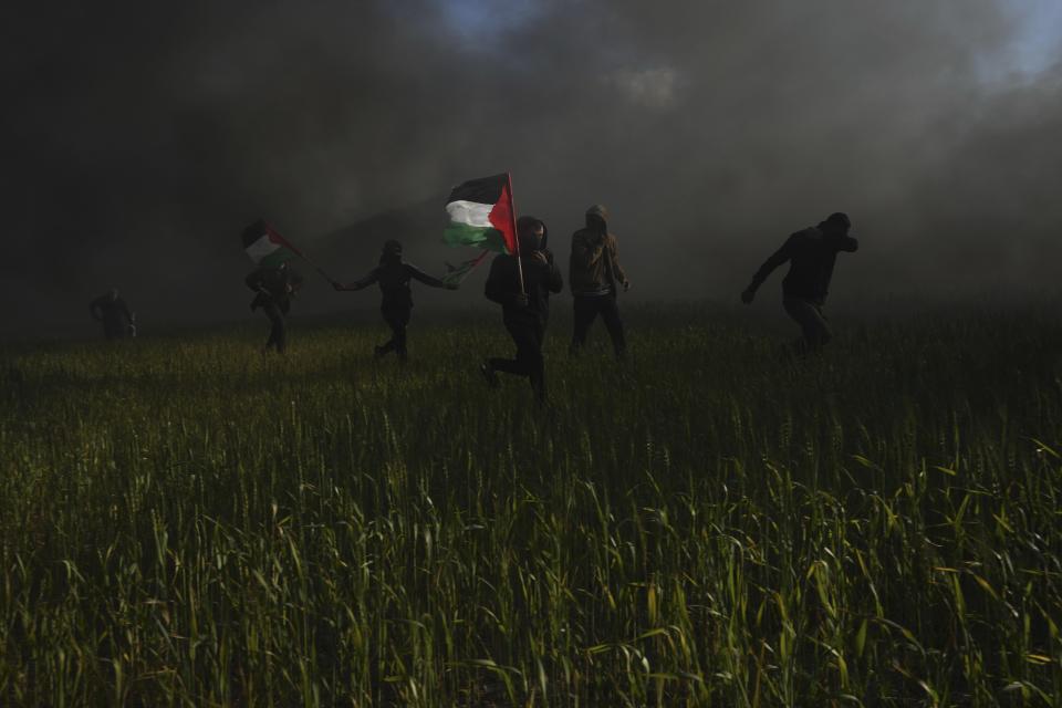 Palestinians carry national flags during a protest against Israeli military raid in the West Bank city of Nablus, along the border fence with Israel, east of Gaza City, Wednesday, Feb. 22, 2023. Palestinian officials say several Palestinians have been killed and over a hundred were wounded during a rare daytime Israeli army arrest raid in the occupied West Bank. The Palestinian Health Ministry says a 72-year-old man was among the dead. The raid took place on Wednesday in the city of Nablus, a scene of frequent military activity. (AP Photo/Adel Hana)