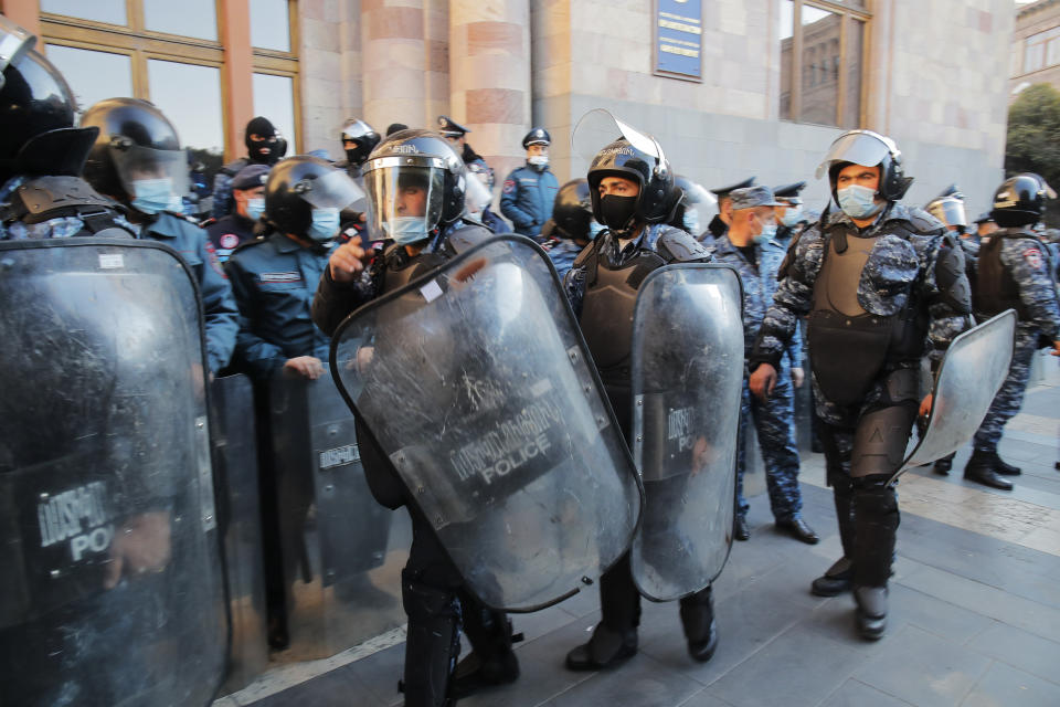 Police guard during a protest against an agreement to halt fighting over the Nagorno-Karabakh region, in front of the government building in Yerevan, Armenia, Wednesday, Nov. 11, 2020. Thousands of people flooded the streets of Yerevan once again on Wednesday, protesting an agreement between Armenia and Azerbaijan to halt the fighting over Nagorno-Karabakh, which calls for deployment of nearly 2,000 Russian peacekeepers and territorial concessions. Protesters clashed with police, and scores have been detained. (AP Photo/Dmitri Lovetsky)