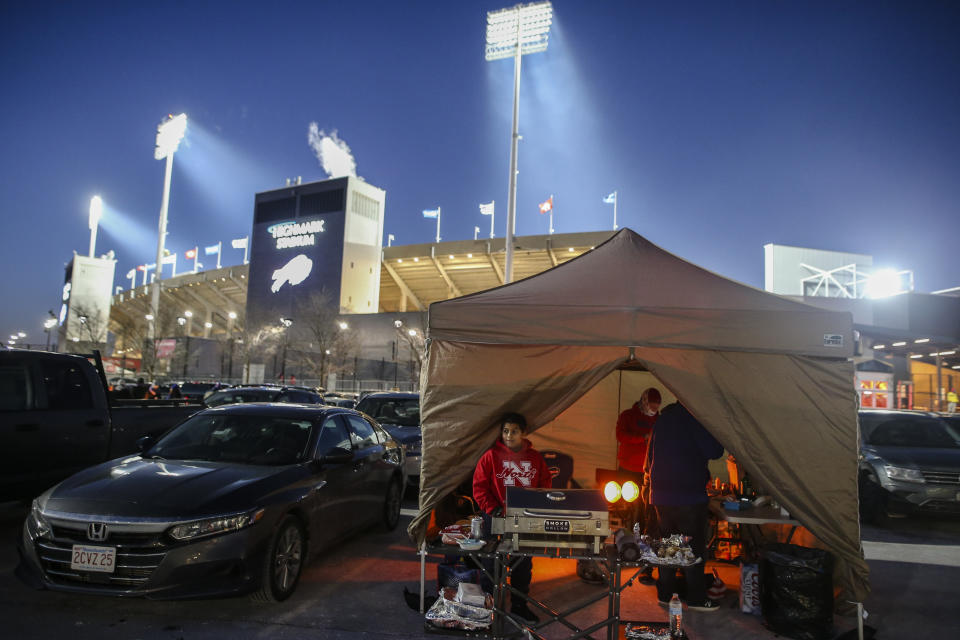 The Ammons and McFadden families tailgate inside a tent as temperatures drop in the parking lots outside of Highmark Stadium before an NFL wild-card playoff football game between the Buffalo Bills and the New England Patriots, Saturday, Jan. 15, 2022, in Orchard Park, N.Y. (AP Photo/Joshua Bessex)