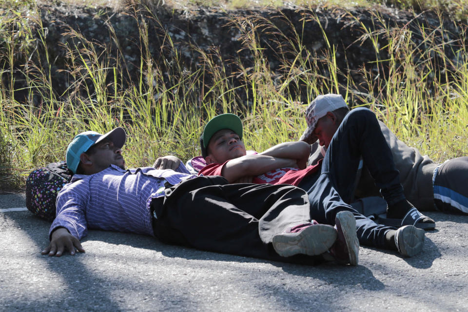Migrants lie on the side of the road on their way North near Agua Caliente, close to the border with Guatemala, Thursday, Dec. 10, 2020. Honduran security forces stationed on the highway a few kilometers before Agua Caliente, asked the migrants for their passports or identity cards and proof of a COVID-19 test, and if they did not produce those documents they would not be allowed to move on. (AP Photo/Delmer Martinez)