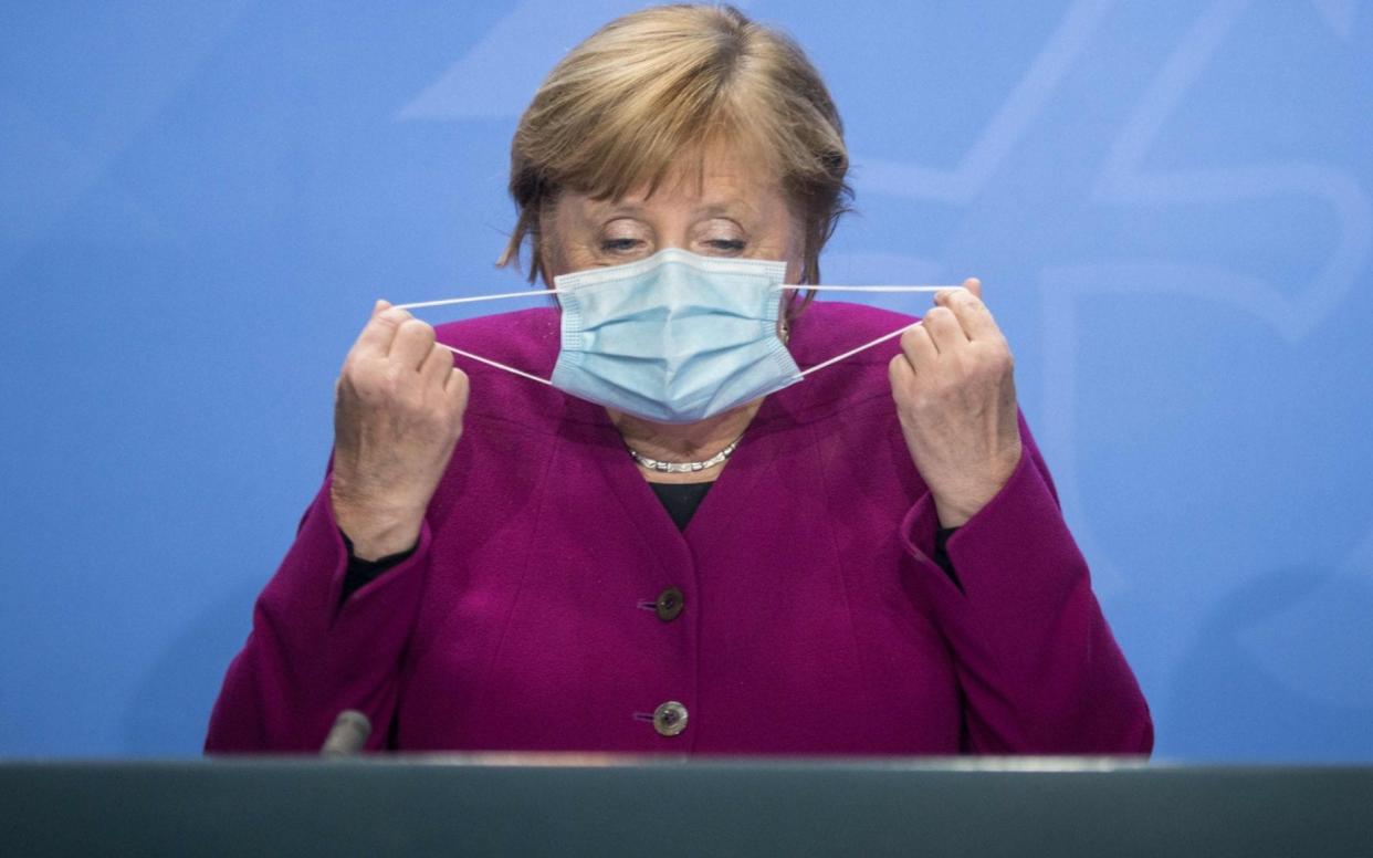 Angela Merkel takes off her mask to talk to reporters after meeting the leaders of Germany's federal states - STEFANIE LOOS/AFP
