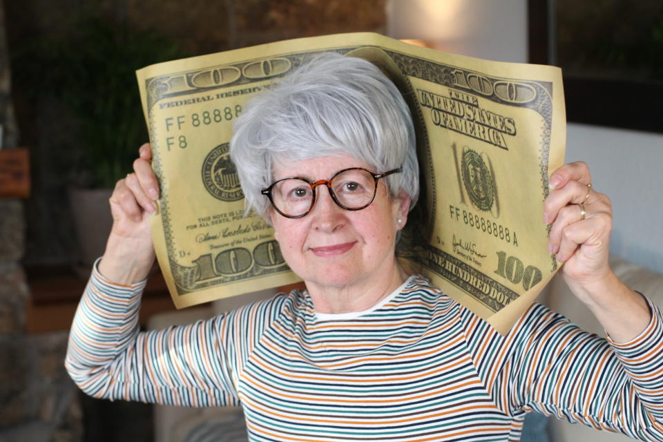 Senior woman holding gigantic dollar bill.