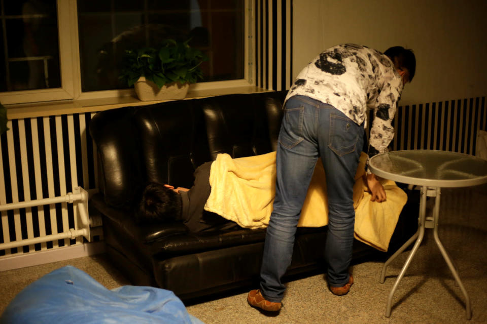 Cui Meng, a co-founder of Goopal Group, covers employee Li Yan with a blanket as Li takes a nap on a sofa during a break at work around midnight in Beijing on April 19, 2016. (Jason Lee/Reuters)