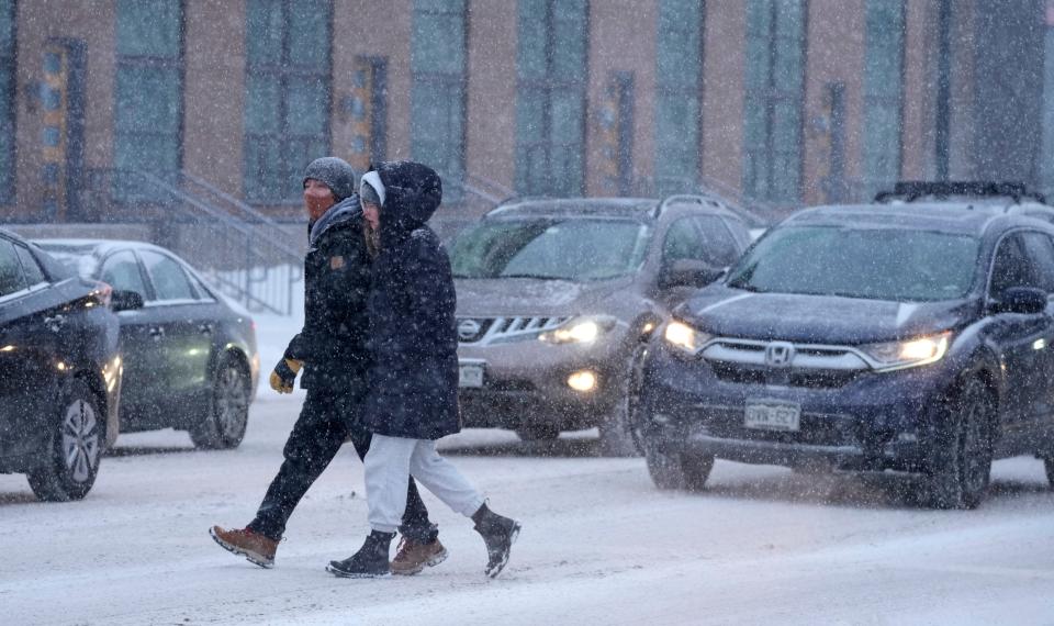 A couple bundled against the cold temperatures cross Speer Boulevard as motorists struggle in heavy traffic along the eastbound lanes as a late winter storm brings heavy snow during the evening rush Wednesday, March 9, 2022, in Denver.