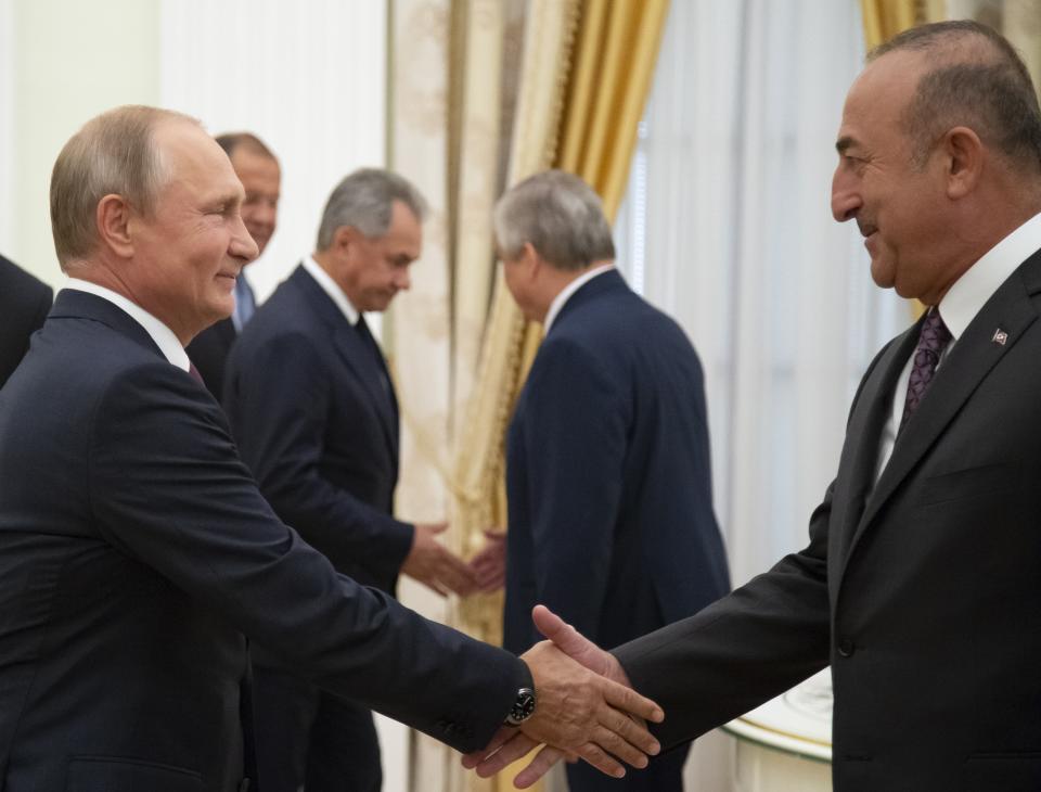 Russian President Vladimir Putin, left, shakes hands with Turkish Foreign Minister Mevlut Cavusoglu during their meeting in the Kremlin in Moscow, Russia, Friday, Aug. 24, 2018. Turkey's Foreign Minister on Friday warned against a possible Syrian government offensive on the last remaining stronghold of opposition against President Bashar Assad, while Russia indicated that it's losing its patience with the rebels. (AP Photo/Alexander Zemlianichenko, Pool)