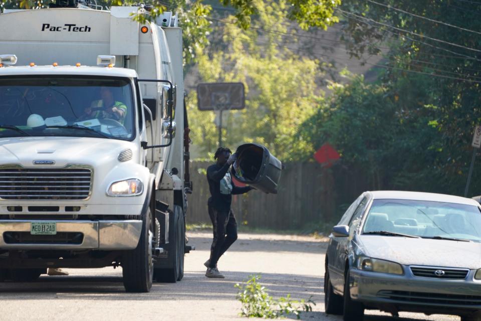 A Richard's Disposal employee replaces a residential garbage can after dumping its contents in a rear loading trash truck, Friday morning, Oct. 7, 2022, in Jackson,