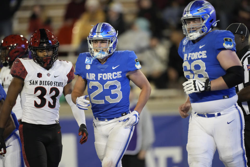 Air Force wide receiver Dane Kinamon, center, celebrates with offensive tackle Mark Heistand, right, after making a touchdown as San Diego State safety Patrick McMorris looks on in the second half of an NCAA college football game Saturday, Oct. 23, 2021, at Air Force Academy, Colo. (AP Photo/David Zalubowski)