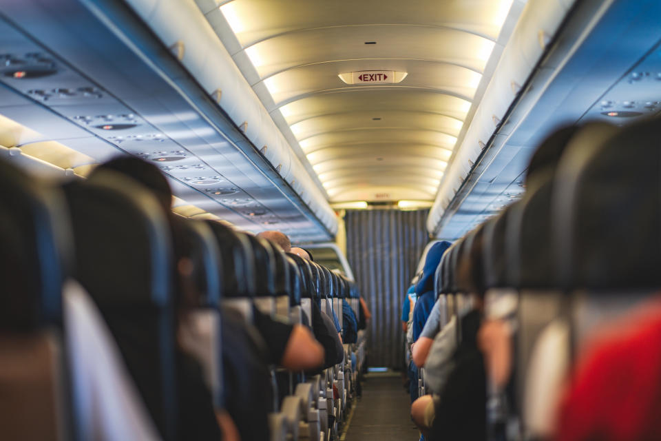 Passengers are sitting and sleeping on an airplane. They get stuck in their seat in a long and boring flight.