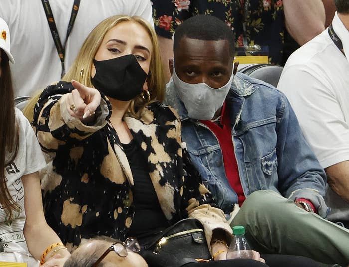 Adele and Rich, both wearing masks, sitting courtside at an NBA Finals game