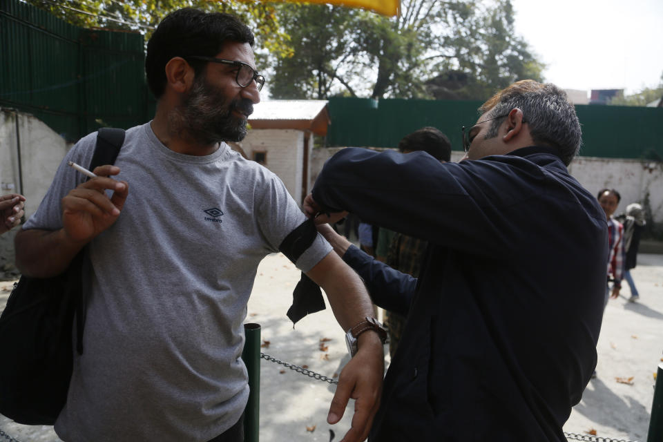 A Kashmiri journalist ties a black band on a colleague before a protest against the communication blackout in Srinagar, Indian controlled Kashmir, Thursday, Oct. 3, 2019. For the last two months, mobile phones and internet services have been shut down in the valley after New Delhi stripped Indian-controlled Kashmir of its semi-autonomous powers and implemented a strict clampdown, snapping communications networks, landlines and mobile Internet. (AP Photo/Mukhtar Khan)