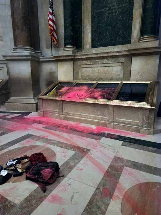 Pink powder is seen on the casement of the U.S. Constitution inside the National Archives Rotunda in Washington, Feb. 14, 2024. The National Archives building and galleries were evacuated after two protesters dumped powder on the protective casing around the U.S. Constitution. (William J. Bosanko/National Archives via AP)