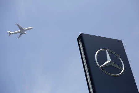 FILE PHOTO: A plane flies above as a Mercedes-Benz logo is seen outside its Shanghai office, August 5, 2014. REUTERS/Aly Song
