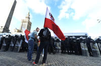 Polish police face protesters angry over new restrictions aimed at fighting the coronavirus pandemic, in Warsaw, Poland, Saturday, Oct. 24, 2020. The protesters included entrepreneurs, far-right politicians, football fans and vaccine opponents. The protesters, many wearing no protective masks, violated a new restriction on gatherings of more people. The clashes come amid rising social tensions and as new restrictions just short of a full lockdown took effect Saturday.(AP Photo/Czarek Sokolowski)