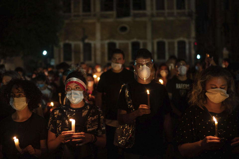 Demonstrators march holding candles honoring the victims of the deadly explosion at Beirut port which devastated large parts of the capital, in Beirut, Lebanon, Sunday, Aug. 9, 2020. (AP Photo/Felipe Dana)
